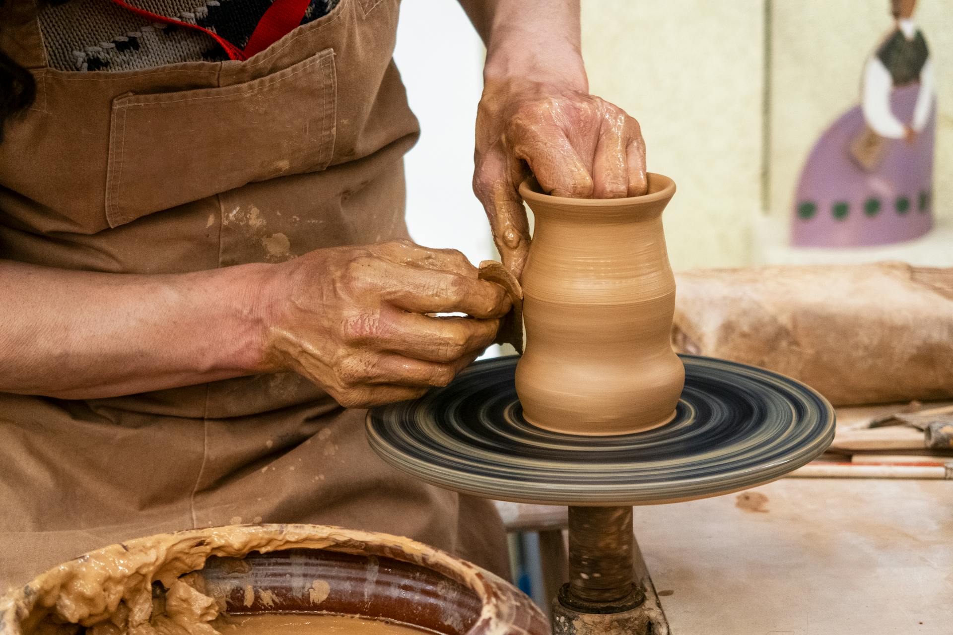 Hands raising a pot on the wheel