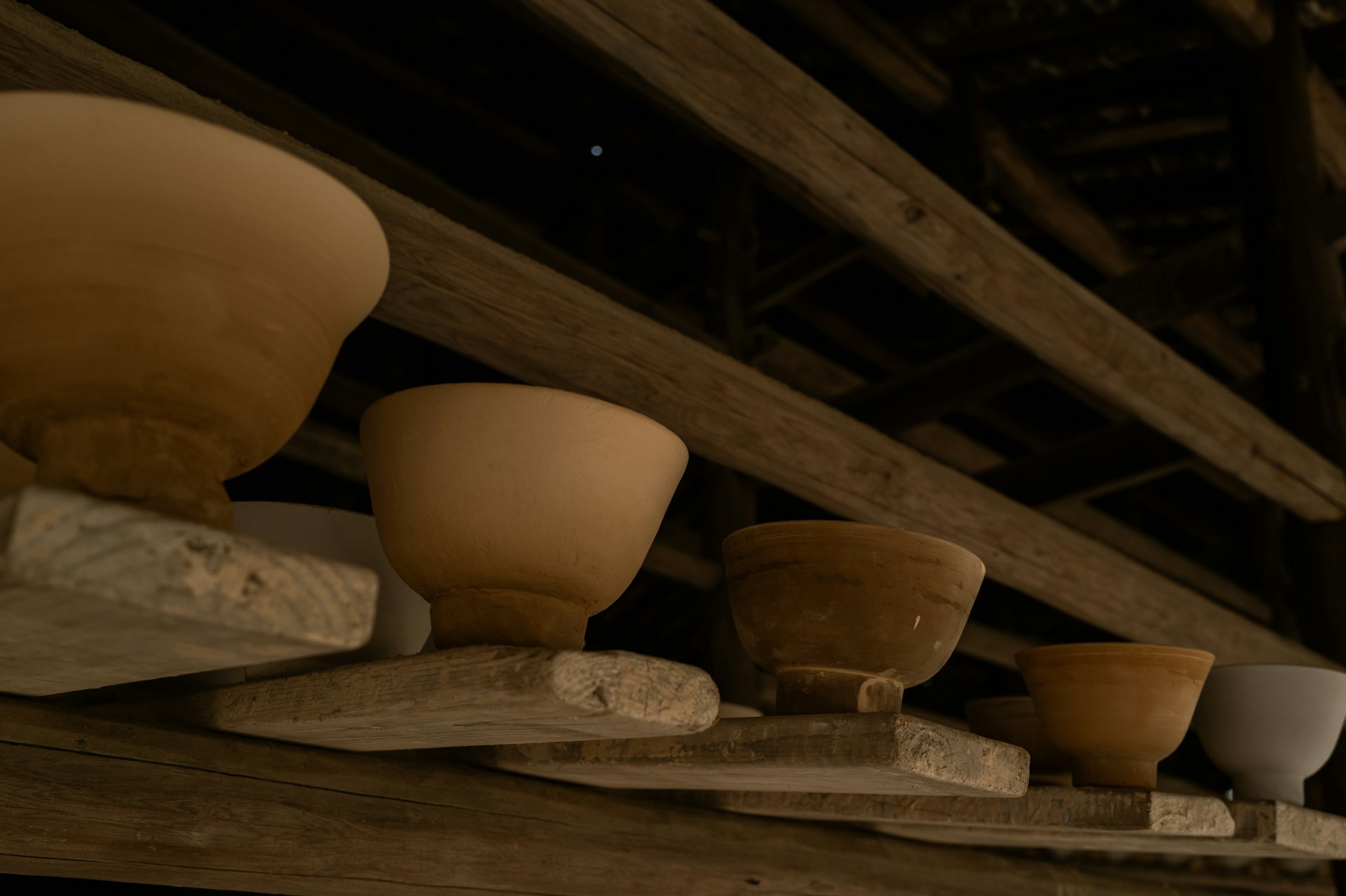 Bisque bowls drying on wooden shelves